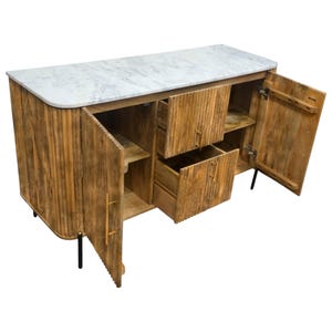K&ouml;nnte beinhalten: Ein Holzsideboard mit wei&szlig;er Marmorplatte. Der Schrank hat zwei T&uuml;ren und zwei Schubladen, alle offen. Die T&uuml;ren und Schubladen haben vertikale Rillen. Der Schrank hat goldfarbene Griffe und schwarze Beine.
