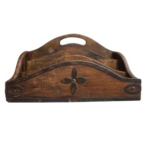 May include: A wooden desk organizer with three compartments and a handle. The organizer is brown with metal accents and a decorative four-petal design in the center. The edges are trimmed with metal.