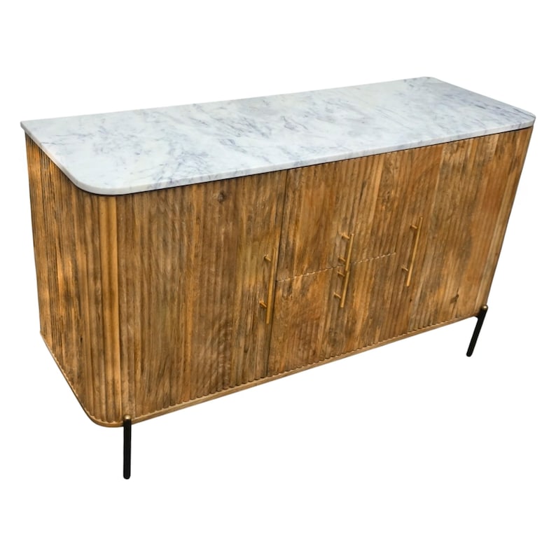 K&ouml;nnte beinhalten: Ein Holzschrank mit einer wei&szlig;en Marmorplatte. Der Schrank hat ein strukturiertes, vertikales Holzmaserungsdesign und goldfarbene Griffe. Er steht auf vier schwarzen Metallbeinen. Der Schrank hat drei T&uuml;ren.