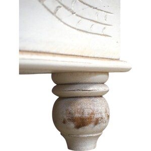 May include: Close-up of a white wooden table leg with a distressed finish. The leg has a rounded ball shape at the bottom and a fluted design above it.