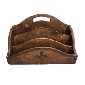 May include: A vintage wooden desk organizer with a handle and three curved compartments. The organizer is stained a warm brown color and features a decorative floral design on the front. The wood has visible grain and a distressed appearance.