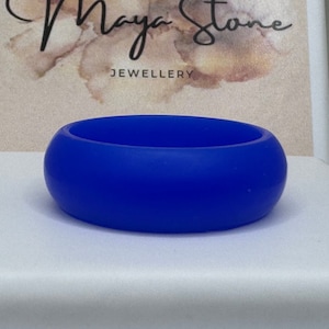 Pode incluir: Um anel de silicone azul brilhante. O anel é liso e tem uma forma arredondada.