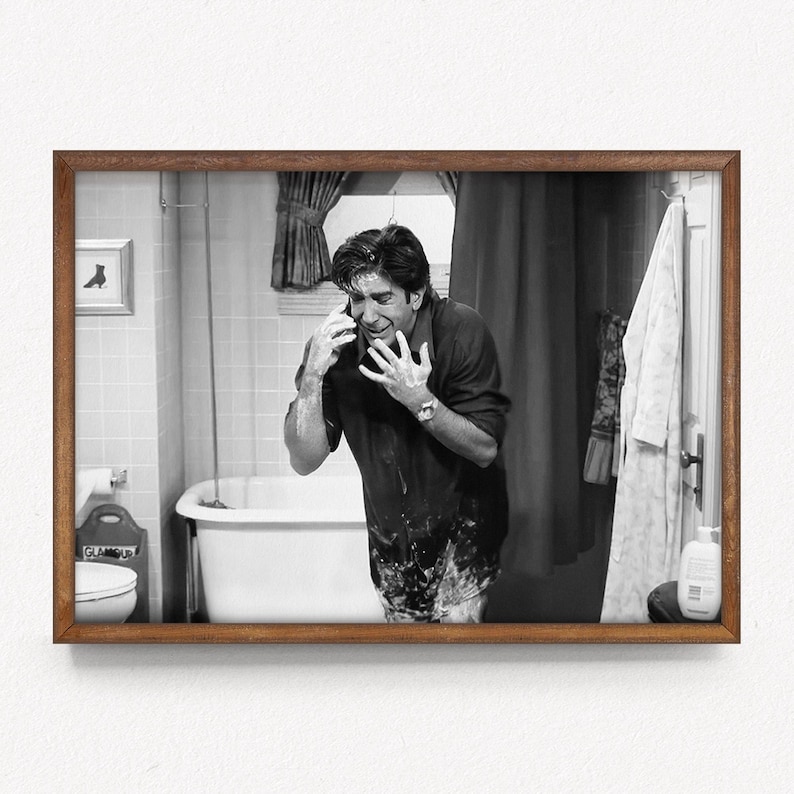 May include: Black and white framed print of a man in a bathroom, talking on a phone while covered in soap. The man is standing in front of a white bathtub, with a towel hanging on the wall.