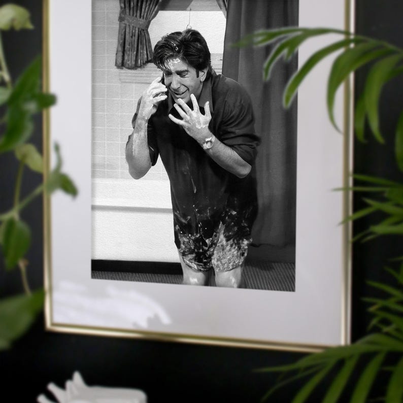 Peut inclure: Tirage encadr&eacute; en noir et blanc repr&eacute;sentant un homme dans une salle de bain, couvert de mousse, parlant au t&eacute;l&eacute;phone. Le cadre est dor&eacute;. L'image est sur fond sombre avec du feuillage vert.