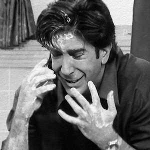 Peut inclure: Image en noir et blanc d'un homme souriant au t&eacute;l&eacute;phone. Ses mains et son front sont couverts d'une substance blanche. Il porte une chemise sombre &agrave; col.