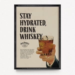 May include: A framed vintage advertisement for Jack Daniel's whiskey. The poster features the text "STAY HYDRATED, DRINK WHISKEY" above a hand holding a glass of whiskey with ice. The ad includes the Jack Daniel's logo and additional text.