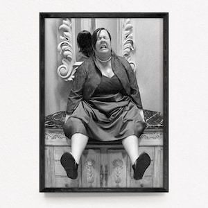 Könnte beinhalten: Schwarz-weiß gerahmtes Kunstwerk einer Person, die auf einer dekorativen Oberfläche sitzt, mit einem Spiegel im Hintergrund. Die Person trägt ein dunkles Kleid und eine Jacke mit einer Perlenkette. Das Kunstwerk ist eine Bleistiftzeichnung.