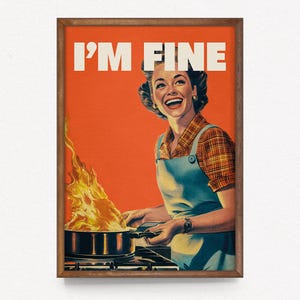 May include: A framed vintage-style print with the text "I'M FINE" above a woman smiling while cooking, with flames erupting from a pot on the stove. The woman wears a blue apron and a plaid shirt against an orange background.
