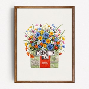 Könnte beinhalten: Ein gerahmter Druck mit einer Yorkshire Tea-Schachtel, die mit einem bunten Strauß Wildblumen geschmückt ist. Der Strauß enthält blaue Kornblumen, gelbe Gänseblümchen und orangefarbene Mohnblumen. Der Text "Yorkshire Tea" ist deutlich sichtbar.