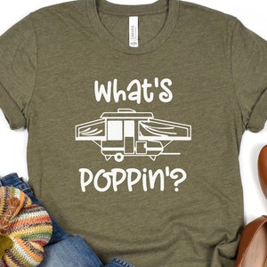 May include: A green t-shirt with white text that says "What's Poppin'?" and a white illustration of a pop-up camper.