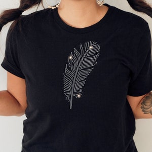 Könnte beinhalten: Ein schwarzes T-Shirt mit einem Strass-Feder-Design.