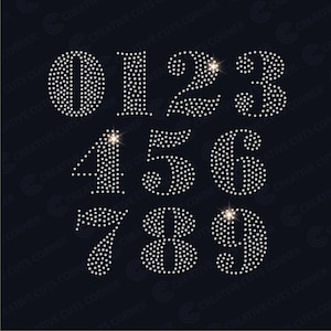 May include: A set of ten silver rhinestone numbers, 0 through 9, on a black background. Each number is made of small, sparkling rhinestones.