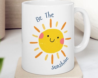 May include: White ceramic mug with a yellow sun graphic and the text "Be The Sunshine".