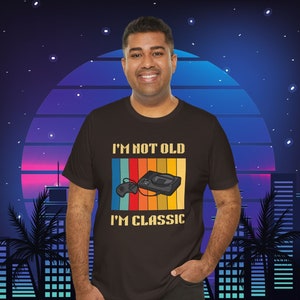 May include: A black t-shirt with a retro-style graphic that says "I'm not old I'm classic" with a Sega Genesis console and controller.