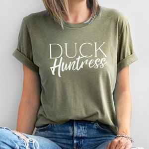 May include: A green t-shirt with the text "DUCK Huntress" in white lettering.