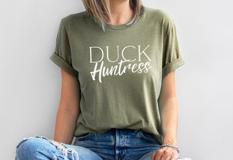 May include: A green t-shirt with the text "DUCK Huntress" in white lettering.