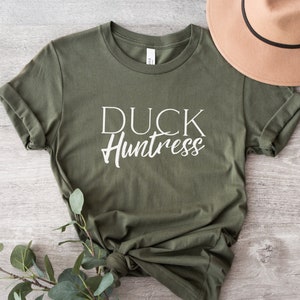 May include: A green t-shirt with the text "DUCK Huntress" in white lettering.