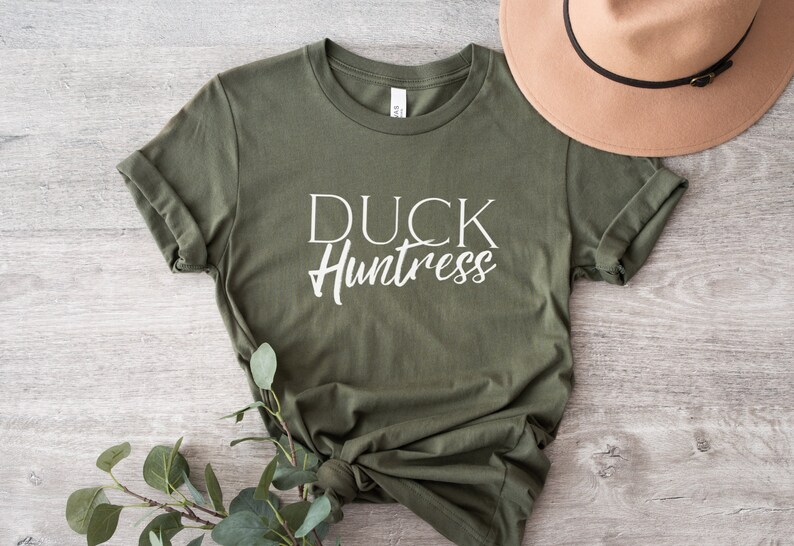 May include: A green t-shirt with the text "DUCK Huntress" in white lettering.