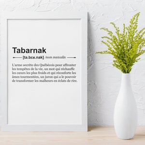 May include: A white framed print with a black and white definition of the word "Tabarnak" in French. The definition is written in a simple font and includes the phonetic pronunciation of the word. The print is hanging on a white wall with a vase of green flowers in front of it.