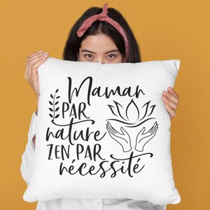 May include: White pillow with black text that reads "Maman par nature zen par n&eacute;cessit&eacute;". The text is in a cursive font and includes a floral design and a hand gesture.