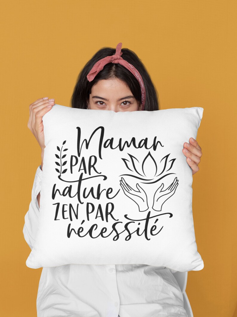 May include: White pillow with black text that reads "Maman par nature zen par n&eacute;cessit&eacute;". The text is in a cursive font and includes a floral design and a hand gesture.
