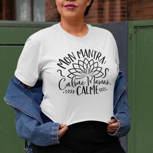 May include: White t-shirt with a black graphic design featuring a lotus flower and the text "Mon Mantra: Calme Maman, CALME".