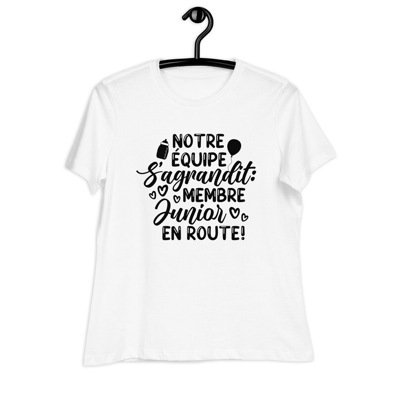 May include: White t-shirt with black text that reads "Notre &eacute;quipe s'agrandit: Membre Junior en route!" with a baby bottle, balloon, and hearts.