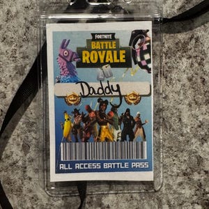 May include: A clear plastic badge holder with a black lanyard. The badge insert features the words "Fortnite Battle Royale" and "Daddy" above a group of cartoon characters. The bottom of the insert reads "ALL ACCESS BATTLE PASS".