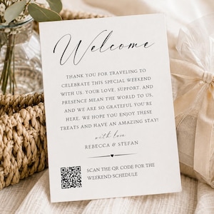 May include: A white rectangular welcome card featuring black text that reads Welcome, thank you for traveling to celebrate this special weekend with us, with love, Rebecca & Stefan, and a QR code to scan for the weekend schedule.