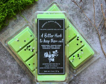 Könnte beinhalten: Zwei durchsichtige Kunststoffbehälter gefüllt mit hellgrünem Sojawachs-Duftwachs. Das mittlere Etikett lautet: Krafty Kitty Studios, The Spellcaster Collection, A Bitter Herb to keep them out, Wormwood, Crushed Herbs, Moss, Patchouli, Balsam, Chamomile, Peppercorn, Scented Soy Wax Melts, Made in Florida, Hand Poured in Small Batches, Net wt. 2 oz / 57 g.