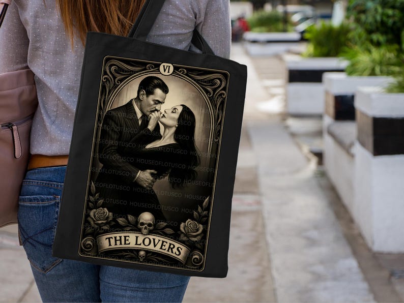 Tarot-inspired “The Lovers” tote bag capturing the passionate Morticia and Gomez Addams dynamic. A must-have gothic gift for Addams Family fans, dark romance readers, and vintage art collectors. Handmade by House of Lotus Co on premium black canvas, this mystical tote blends gothic beauty, classic love symbolism, and art deco tarot design.