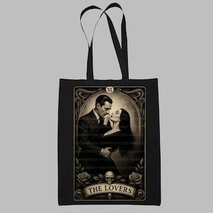 “The Lovers” Addams Family tote bag inspired by the timeless romance of Morticia and Gomez Addams. This gothic tarot art tote is a perfect handmade gift for spooky season, Halloween fans, and lovers of macabre elegance. Designed by House of Lotus Co, featuring intricate vintage detailing, skull accents, and romantic Victorian flair on durable black cotton canvas.
