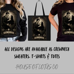 May include: Black sweatshirt, tote bag, and t-shirt featuring a vintage tarot card design of a couple embracing, with roses, skulls, and the text "THE LOVERS." The image also includes the text "ALL DESIGNS ARE AVAILABLE AS CREWNECK SWEATERS, T-SHIRTS & TOTES."