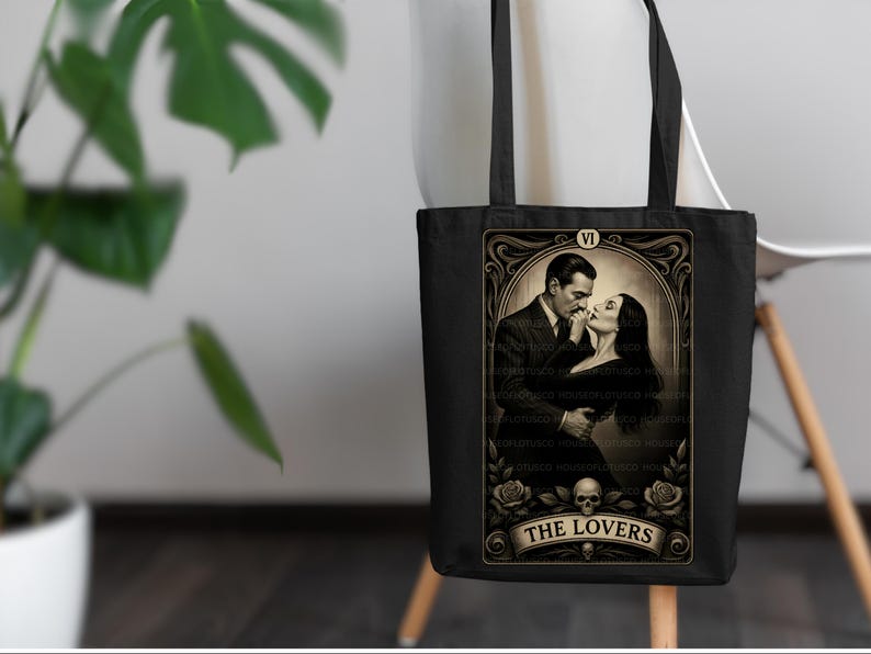 Elegant black tote bag with “The Lovers” tarot artwork inspired by Morticia and Gomez Addams. A perfect handmade Halloween gift for fans of gothic romance, witchy style, and timeless love. Designed by House of Lotus Co, this durable cotton tote embodies dark elegance and tarot symbolism with vintage gold detailing and romantic Addams Family aesthetic.