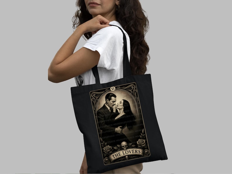 Black canvas tote bag featuring “The Lovers” tarot-inspired design inspired by Morticia and Gomez Addams. Perfect gothic romance gift for Addams Family fans, Halloween lovers, and dark aesthetic admirers. Handmade by House of Lotus Co, this high-quality tote celebrates eternal love, passion, and mystery with vintage-style tarot artwork in sepia tones.