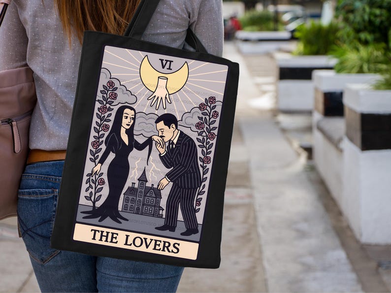 Hand-pressed tote bag featuring Addams Family-inspired tarot design The Lovers. Gothic romantic art with roses, mansion, and crescent moon. Great Halloween tote for witchy fashion lovers.