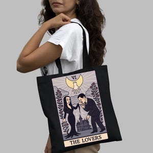 “The Lovers” tarot card tote bag inspired by Morticia & Gomez Addams. Gothic spooky artwork with mansion and moonlight. Handmade organic cotton bag perfect for Halloween or dark romance style.