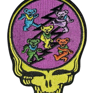 May include: Embroidered patch featuring a yellow skull with a purple background. Five colorful dancing bears in blue, purple, yellow, green, and orange are inside the skull. The patch has a black border and a yellow outline.