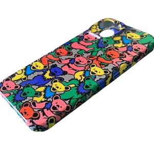 May include: A colorful phone case featuring a repeating pattern of dancing bears in various colors, including pink, yellow, green, blue, and orange. The case has a glossy finish and a cutout for the camera and other phone features.