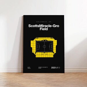 May include: A black poster with the text "ScottsMiracle-Gro Field" in white. A yellow stadium diagram is below the text. The poster includes the location, capacity, and the year 2021.
