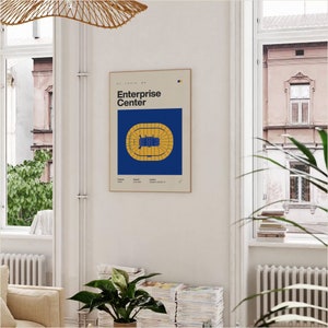 May include: A blue and yellow poster with the text "Enterprise Center" and a diagram of the arena floor plan. The poster is framed and hanging on a white wall.