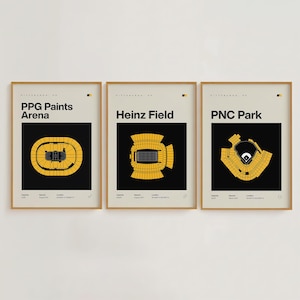 May include: Three framed prints displaying stadium schematics. The prints feature PPG Paints Arena, Heinz Field, and PNC Park, each with a black background and yellow stadium design. The prints are in a neutral colour palette.