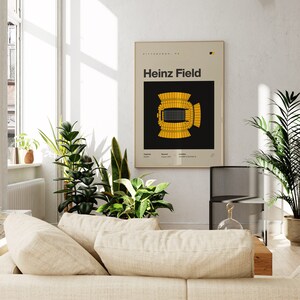 Puede incluir: Un p&oacute;ster en blanco y negro con un contorno de estadio amarillo. El p&oacute;ster tiene el texto "Heinz Field" en letras blancas y el texto "Pittsburgh, PA" en letras blancas m&aacute;s peque&ntilde;as. El p&oacute;ster est&aacute; colgado en una pared blanca.