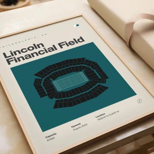May include: Framed art print of Lincoln Financial Field in Philadelphia, PA. The teal and black stadium illustration includes the capacity, opening date, and location coordinates. The print is in a light wood frame.