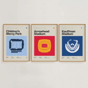 May include: Three framed art prints featuring stadium schematics. The prints showcase Children's Mercy Park, Arrowhead Stadium, and Kauffman Stadium, each with a unique color scheme and design. The text "Kansas City, MO" is at the top of each print.