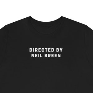 May include: Black t-shirt with white text that reads "DIRECTED BY NEIL BREEN"