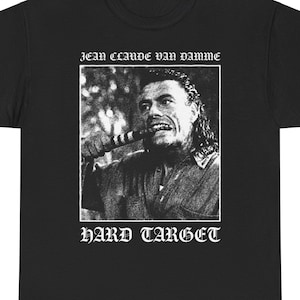 May include: Black t-shirt featuring a white image of Jean-Claude Van Damme from the film Hard Target. The text "Jean-Claude Van Damme" and "Hard Target" is printed in white.