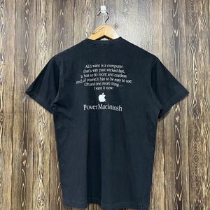 May include: A black short-sleeve t-shirt featuring white text that reads: All I want is a computer that's way past wicked fast, It has to do more and costless. And, of course, it has to be easy to use. Oh, and one more thing... I want it now!