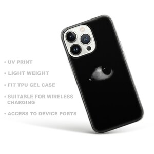 May include: A black phone case with a white eye graphic. The case is made of TPU gel and is compatible with wireless charging.