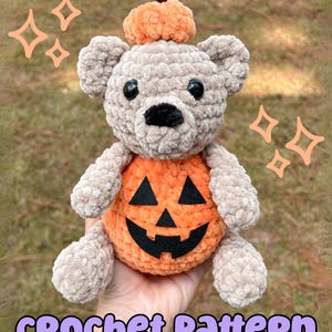 May include: A crocheted bear with a pumpkin body and a pumpkin hat. The bear is light brown with black eyes and nose. The pumpkin body is orange with a black jack-o'-lantern face. The text "CROCHET PATTERN" is at the bottom.